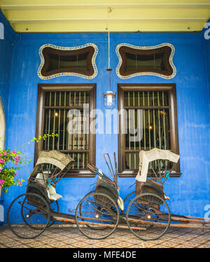 Old rickshaws on the blue wall, Cheong Fatt Tze Mansion, blue villa, Leith Street in George Town, Penang, Malaysia Stock Photo