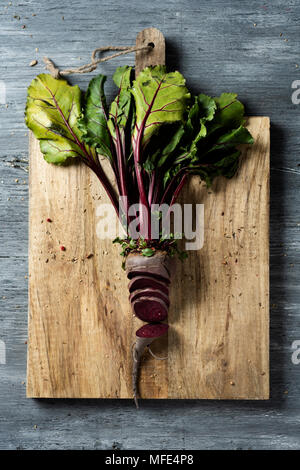 high angle view of a chopped raw beetroot on chopping board, placed on a gray rustic wooden table Stock Photo
