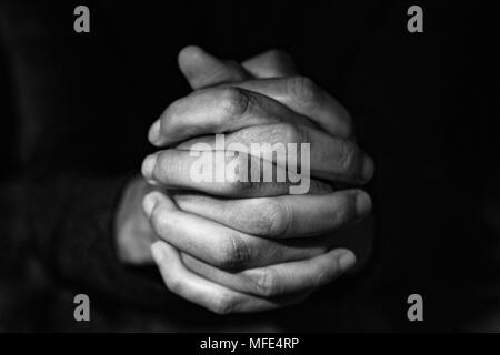 closeup of the hands of a young caucasian man with his hands clasped, in black and white Stock Photo