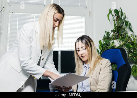 Two young female colleagues having meeting and discussing paperwork. Stock Photo