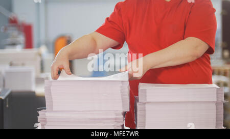 Female hands sorts the stacks of newspapers in typography Stock Photo