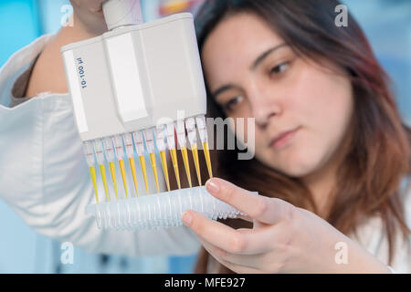 Woman technician with multipipette in genetic laboratory PCR research. Student girl use pipette. Young female scientist loads samples for DNA amplific Stock Photo