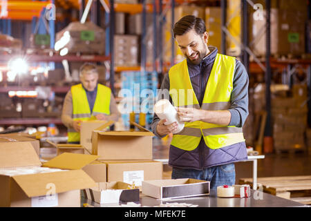 Nice bearded man putting labels on products Stock Photo