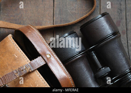 Closeup of old binoculars and leather case on wooden background Stock Photo