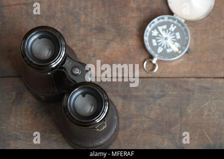 Still life with antique binoculars and compass on wooden background Stock Photo