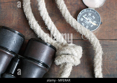 Still life with antique binoculars, rope and compass on wooden background Stock Photo