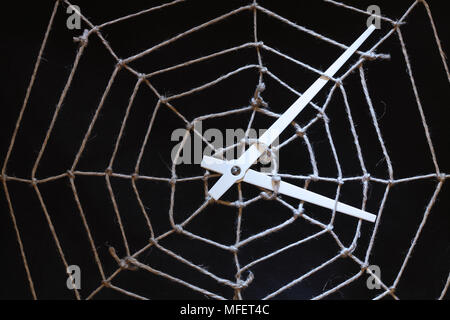Conceptual background with web made from rope and clock hands on dark Stock Photo