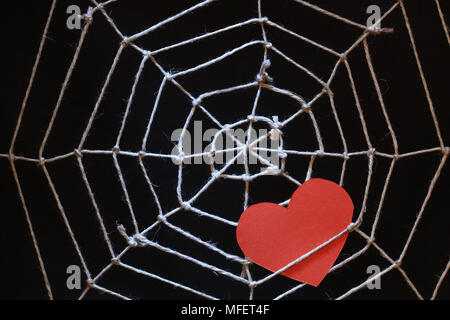 Conceptual background with web made from rope and red paper heart on dark Stock Photo