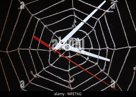 Conceptual background with web made from rope and clock hands on dark Stock Photo