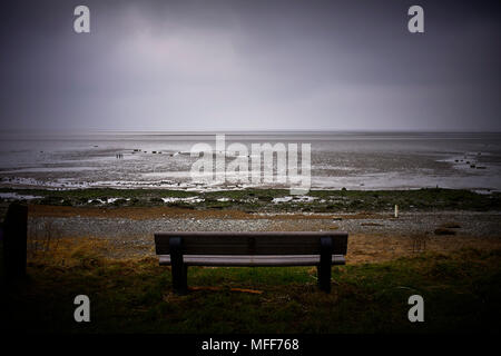 Seat overlooking low tide of Morecambe bay on a cold winter day Stock Photo