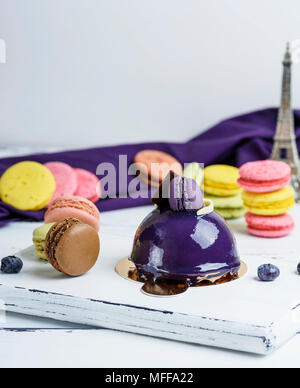 lilac round cake with macarons on a white wooden board, close up Stock Photo