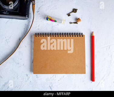 blank notepad on an iron spring with brown sheets and a red wooden pencil on a white background, top view Stock Photo