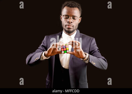 close up portrait of black man in formal clothing playing a puzzle to train his brain. logical game. create own future. solving block Stock Photo
