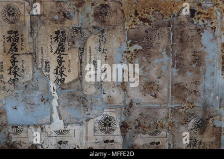 Wall with delicate remnants of old Japanese posters that have been torn off. Beige and light blue with Japanese lettering visible. Close up, artistic. Stock Photo