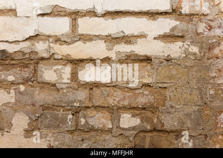 Rough brick wall with white paint coming loose Stock Photo