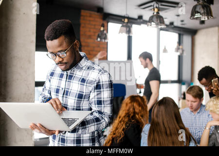 Afro programmer in casual outfit is fixing broken laptop at workplace Stock Photo