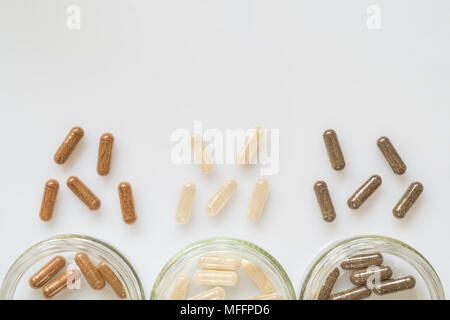 Medicinal capsule spill out of a three plastic bottles on a light surface Stock Photo