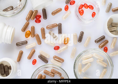 Different medicinal capsule, pills and jars on a light surface Stock Photo