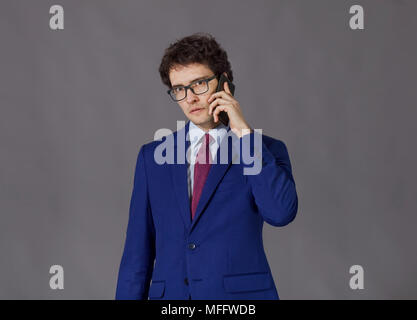 Curly-headed man wearing in blue jacket and glasses talking by mobile phone Stock Photo