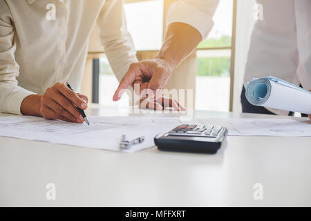 Engineers discuss a blueprint while checking information on a tablet computer in a office. Stock Photo