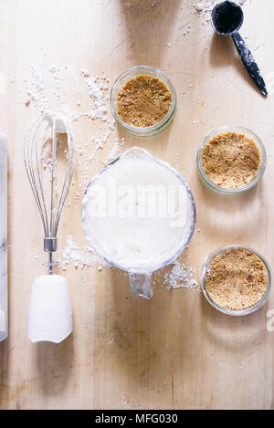 Preparation of a cheesecake on jar without baking it, biscuit mixed with butter are pressed in glass container Stock Photo