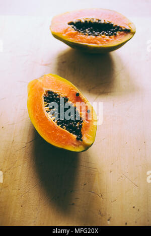 Close up of tropical fruit papaya cut i half on a wooden background Stock Photo