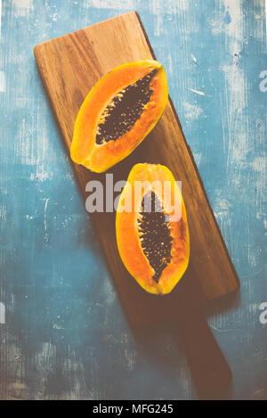 Close up of tropical fruit papaya cut i half on a wooden background Stock Photo