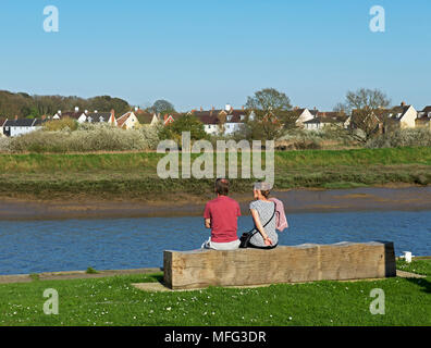 Couple sitting on bench overlooking the River Colne (and Wivenhoe), Essex, England UK Stock Photo