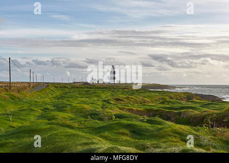 Hook Lighthouse away in the distance on the Hook Peninsula on one fine Autumn evening with the Low sun lighting up the Grass Hummocks. County Wexford, Stock Photo