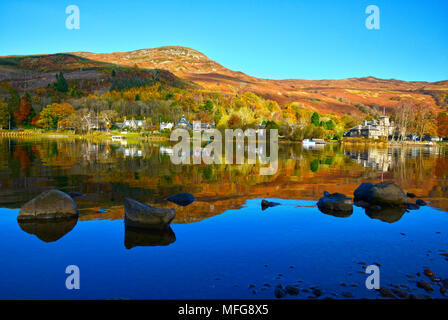 Looking across Loch Earn to St Fillans village, Scotland UK  Autumn colours and reflections clear blue sky sunny day October 2017 Stock Photo