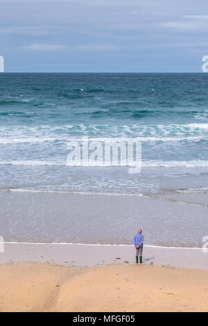 A man standing on the shoreline at Treyarnon Bay on the North Cornwall coast. Stock Photo