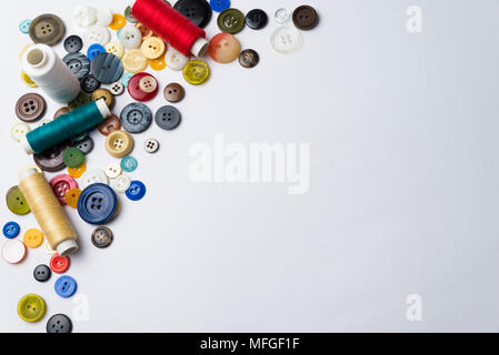 multi-colored buttons and coils with threads lie on a white surface Stock Photo