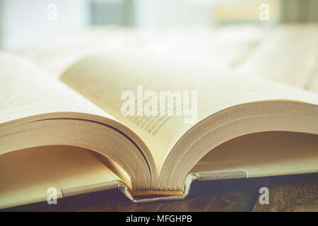 Beautiful high key closeup of an open book with white pages on a wooden table. Reading and literacy concept. Stock Photo