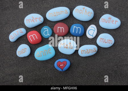 Mother text in many languages with carved and colored stones over black volcanic sand Stock Photo