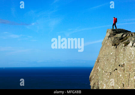 A hiker looks out to sea from cliffs at Fair Head, County Antrim, Ulster, Northern Ireland, Europe Stock Photo