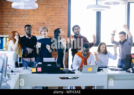 African student is trying to concentrate on his work with laptop while his friends are dancing and having fun. divert attention Stock Photo