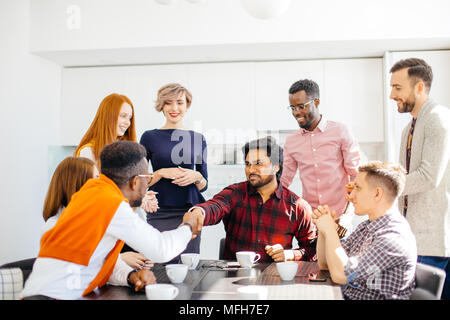 young arrogant intern Hindoo employee is shaking hands with co-workers while drinking coffee. closeup portrait Stock Photo