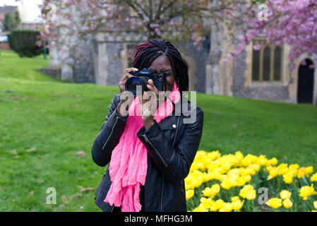 Black lady using a Canon A-1 film camera in the grounds of St Mary's Church in Hemel Hempstead's Old Town Stock Photo
