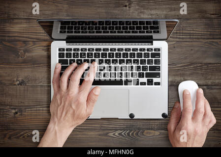 Working on laptop. Top view of man working on laptop laying on the wooden background Stock Photo