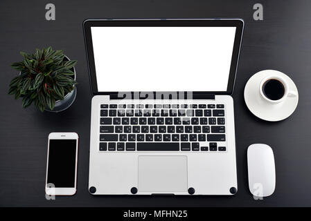 Laptop with blank screen, computer mouse, smartphone and cup of coffee on black table, top view Stock Photo