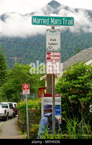 Man with a backpack under the sign that marks the Married Man’s Trail, a path that leads to the former red-light district of Ketchikan, Alaska. Stock Photo