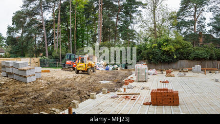 Hitachi heavy plant mechanical digger and Thwaites dumper by the floor slab of a new house under construction on a building site in Surrey, SE England Stock Photo