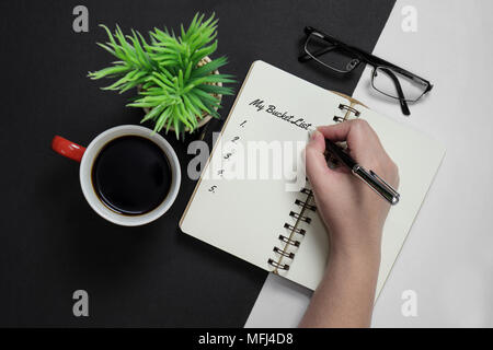 My bucket list. Hand writing on notebook with coffee mug, potted plant and spectacle. Stock Photo