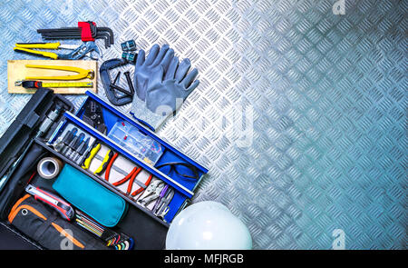 Top view of tools box and helmet on checkered plate background in workshop. Service tools set. Home building and electrical tools. Plumber hand tools. Stock Photo