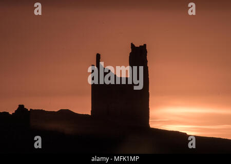 Dunstanburgh Castle, Northumberland. 26th April 2018. The sun rises behind Dunstanburgh castle on a Cloudy day.  Credit: Dan Cooke Credit: Dan Cooke/Alamy Live News Stock Photo