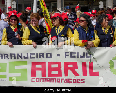 Lisbon, Portugal, 25th April 2018: People are seen in the streets of the popular district of Almada, in Lisbon (Portugal) as they take part in the celebrations of the 44th anniversary of Carnations Revolution. On this occasion, young and old persons,  members of retrired, sport ou music associations, defile in the street, wearing red caps and brandishing red carnations to pay homage to 1974 revolution which drived away the old far right dictatorial regime of António de Oliveira Salazar. Credit: Serge Mouraret/Alamy Live News Stock Photo