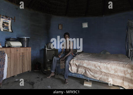 January 12, 2018 - Matatiele, Eastern Cape, South Africa - Luis, 14, sits on the bed in one of his family's mud houses, which he shares with his older brother and father. The blue round shaped house serves as a sleeping room, community area and as a kitchen. (Credit Image: © Stefan Kleinowitz via ZUMA Wire) Stock Photo