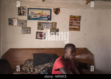 January 12, 2018 - Matatiele, Eastern Cape, South Africa - Jake, 23, sits on his bed and smokes cannabis. He says: 'I have nothing to do all day. I have finished school, but for what? There are no jobs. I am bored, and if I stay at home all day I would become crazy. To keep myself busy I wake up in the morning, then go to town and push people's trollies outside the Spar supermarket. Then I come back home to the village and sell cannabis, and hang out with my friends. I want to find a job and do something meaningful with my life. But there is nothing. You have to be very lucky to find a job aro Stock Photo