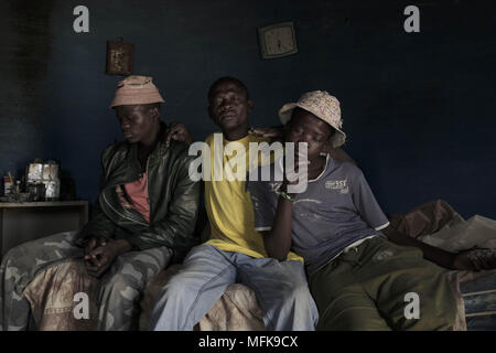 January 12, 2018 - Matatiele, Eastern Cape, South Africa - A father and heavy drinker, sits with his two suns Luis (14) and  Malike (18) on the bed in their mud house. The blue round shaped house serves as a sleeping room, community area and as a kitchen. (Credit Image: © Stefan Kleinowitz via ZUMA Wire) Stock Photo