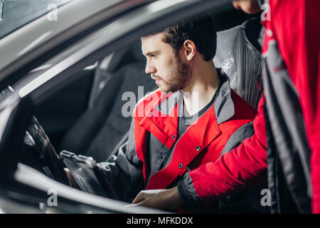 Professional car mechanic working in auto repair service with special laptop for automatic fix Stock Photo